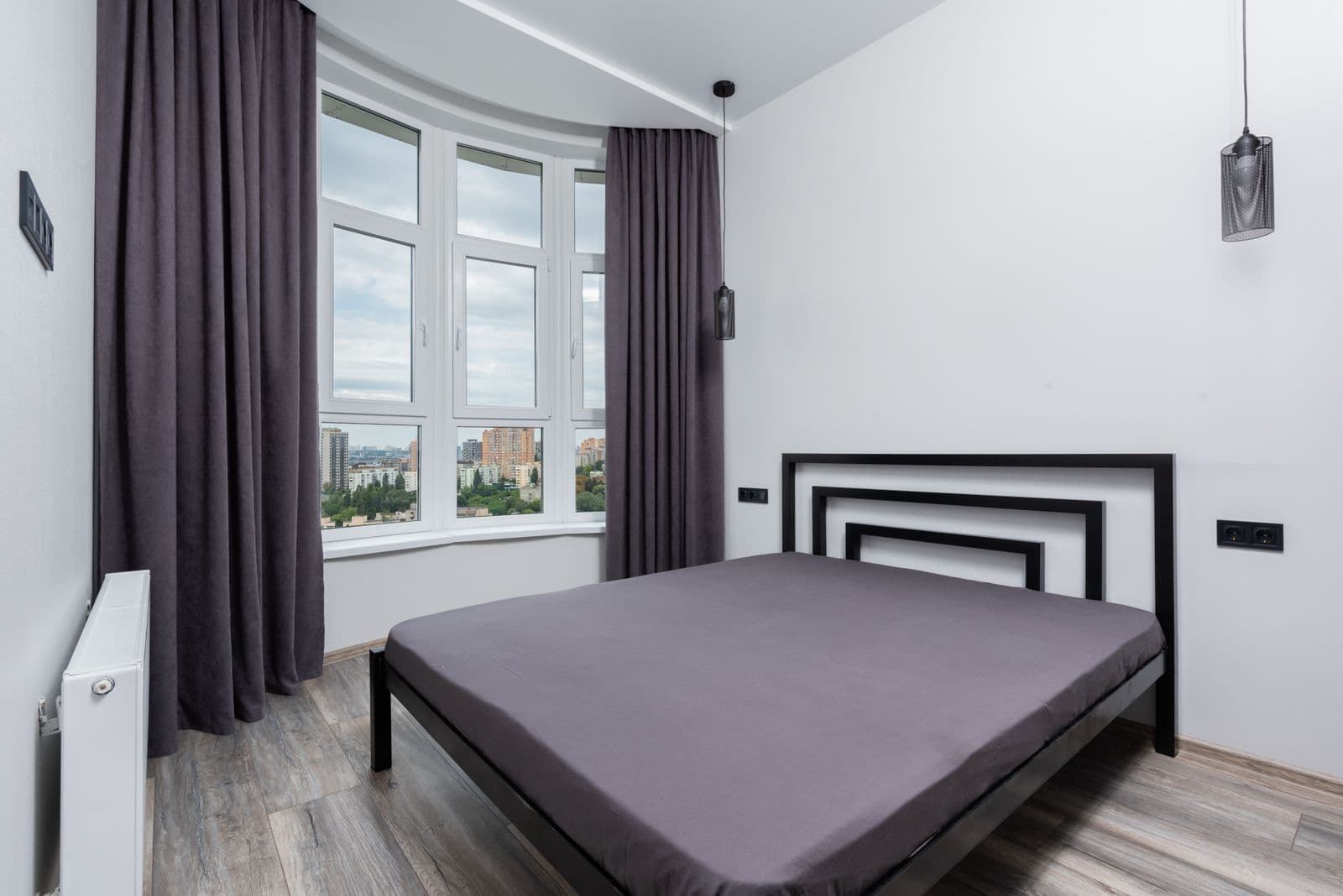 A bedroom with floor-length curtains beside a large window