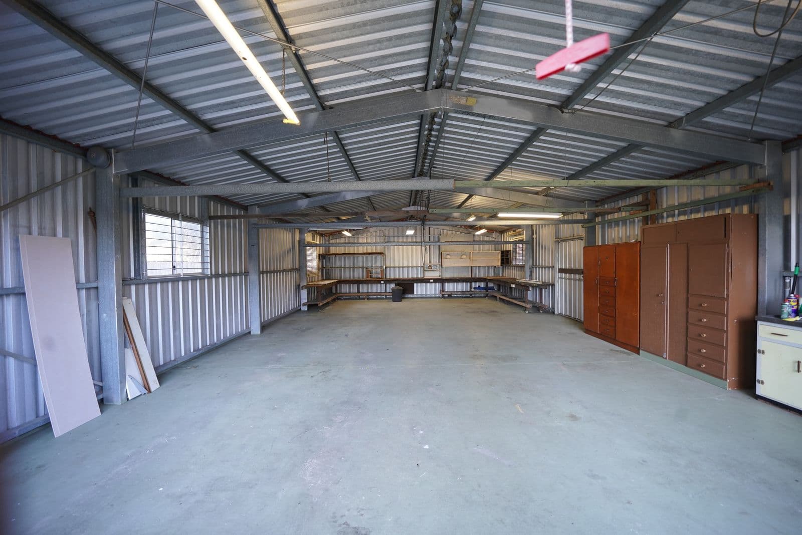 An empty garage with a concrete floor and storage cabinets along one wall