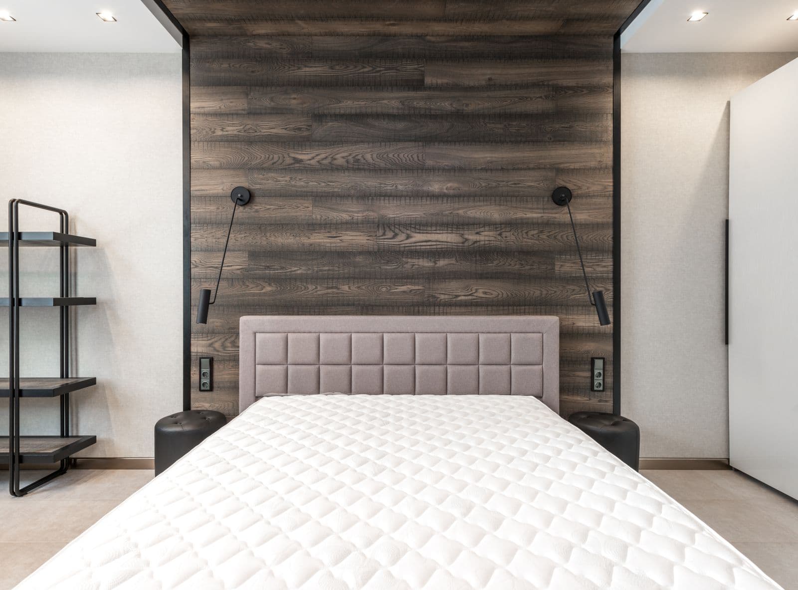 A bare mattress on a bed frame in a plainly furnished bedroom