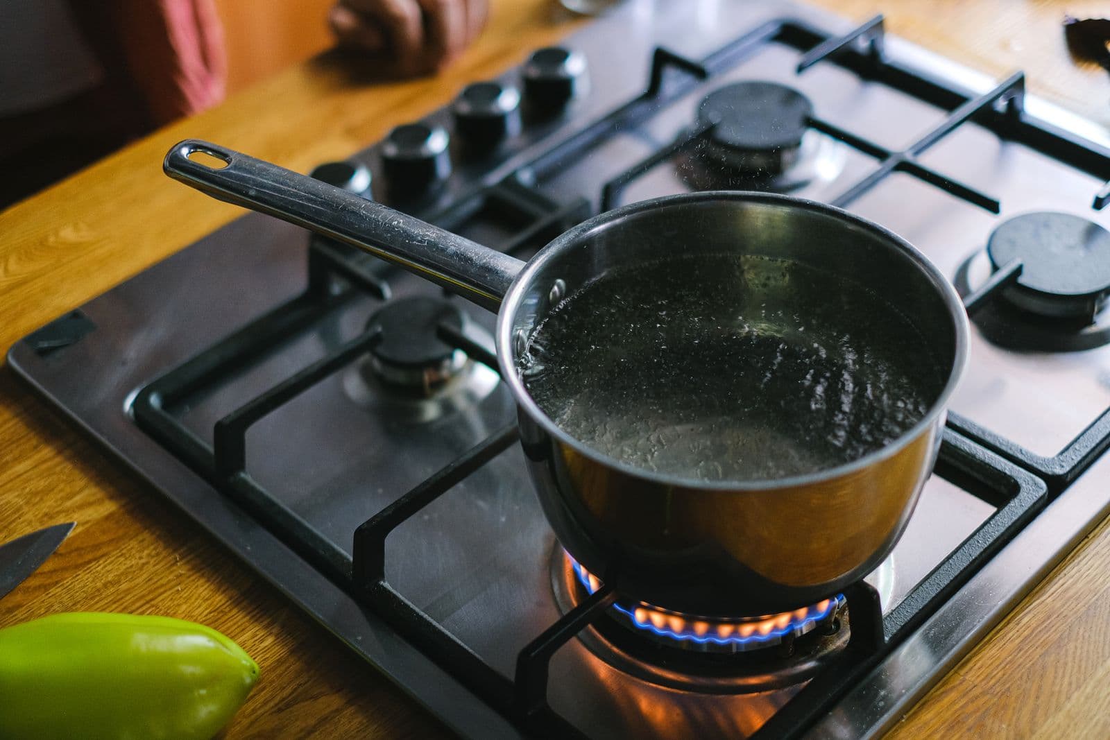 A stainless steel saucepan of water coming to the boil on a gas hob in a home kitchen