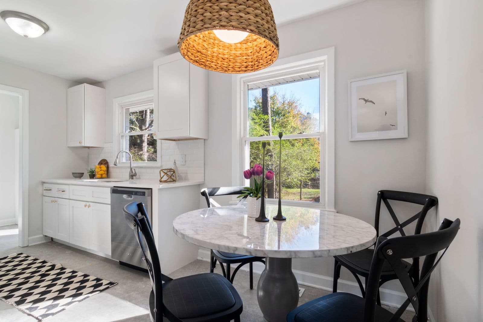 A small kitchen with a round dining table and two chairs by a window