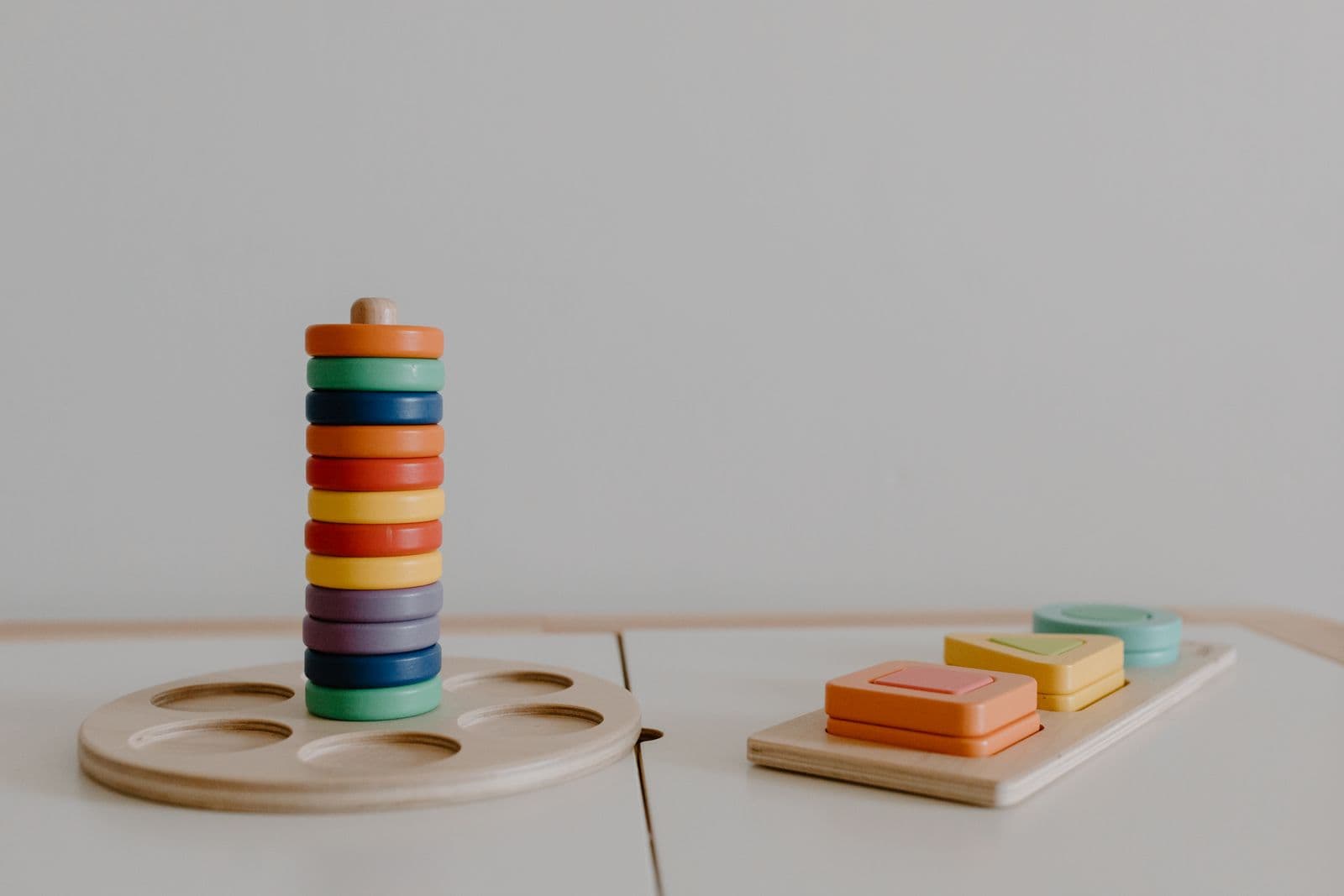 Wooden stacking and sorting toys arranged against a plain wall