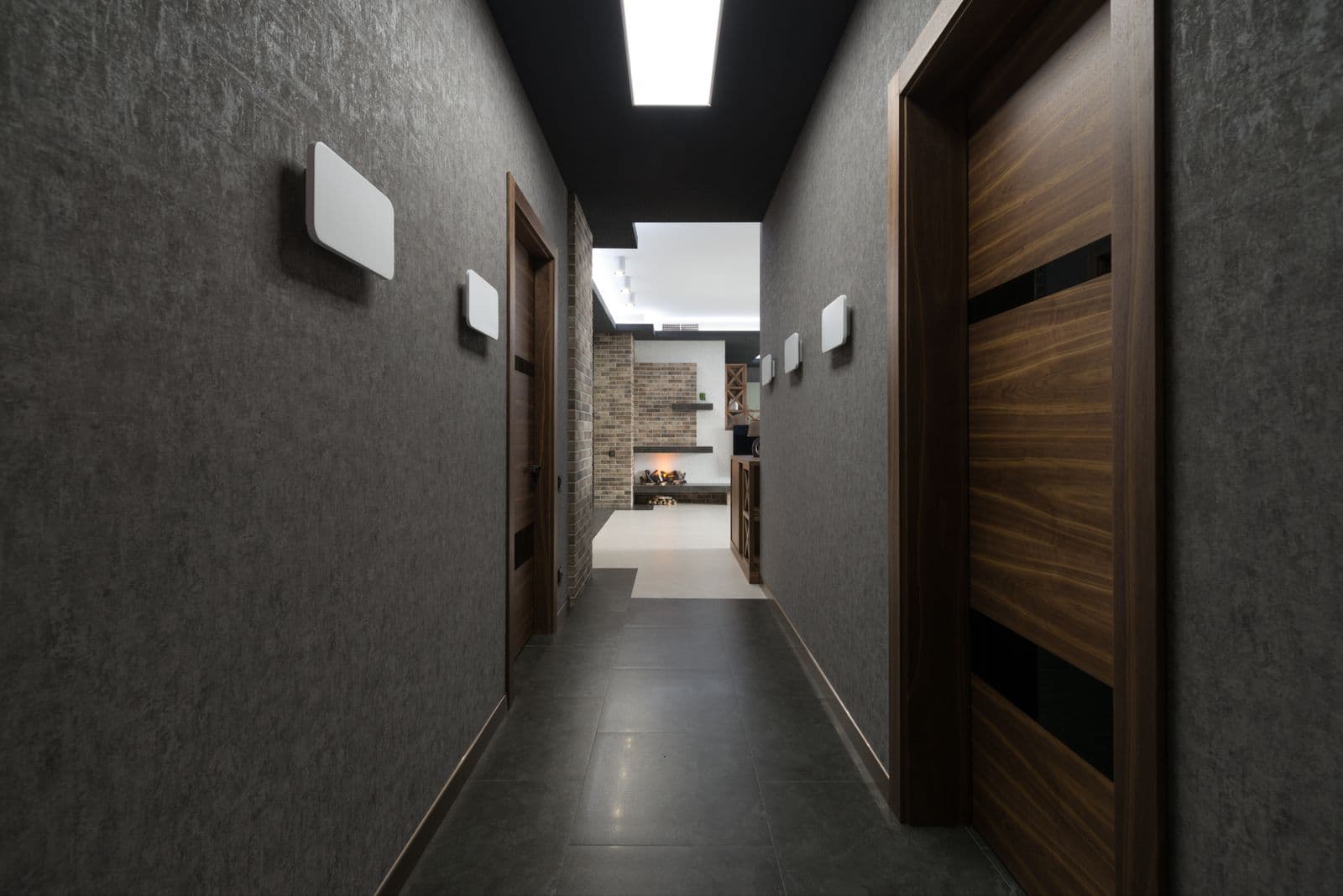A dim apartment corridor running away from the camera towards a lit room