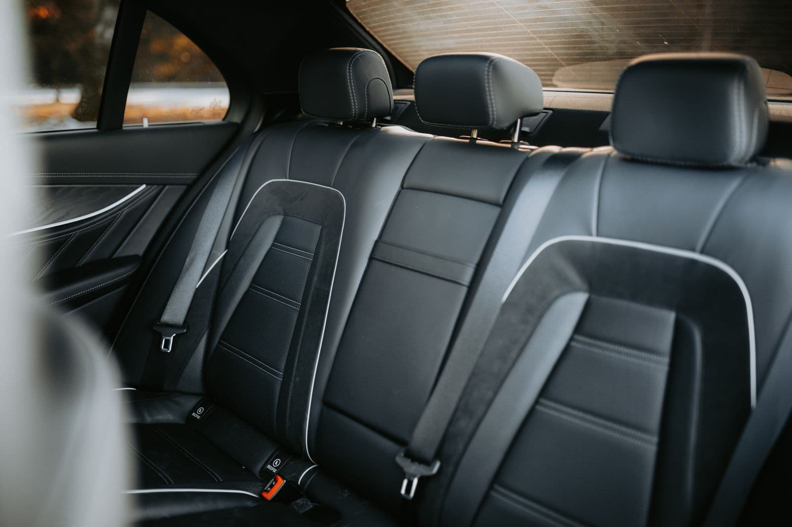 The empty rear bench of a car with the seat belts visible